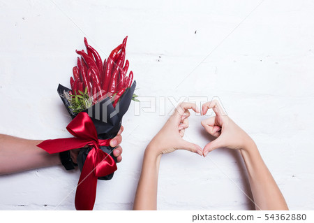 The original unusual edible bouquet of vegetables and fruits on white. Female hand shows heart. The original unusual edible bouquet of vegetables and fruits on white. Female hand shows heart. 54362880