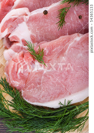 Pork steaks on a wooden cutting board with dill 54365133