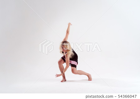 Photo of dancing slender blonde woman looking down in black dress in studio isolated 54366047