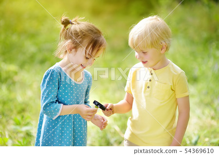 Kids exploring nature with magnifying glass. Close Kids exploring nature with magnifying glass. Close 54369610