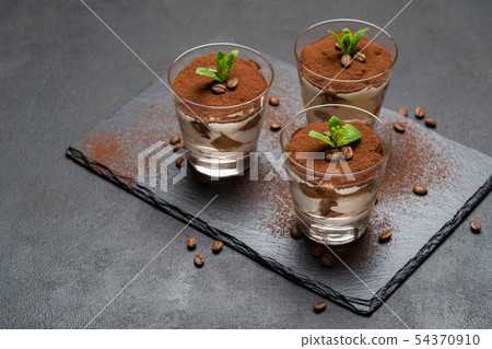 Classic tiramisu dessert in a glass on stone serving board on dark concrete background 54370910