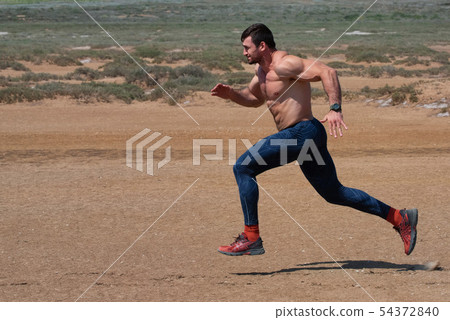 View of topless male athlete running outdoors in nature 54372840