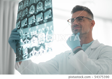 Grey-haired surgeon looking at ultrasound investigation 54375390