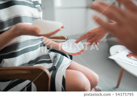 Woman touching breast implants while talking to plastic surgeon 54375795