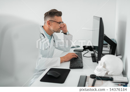 Plastic surgeon feeling busy while working on computer 54376184