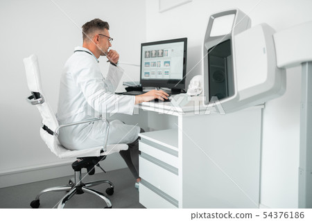Professional plastic surgeon sitting at the computer while working 54376186