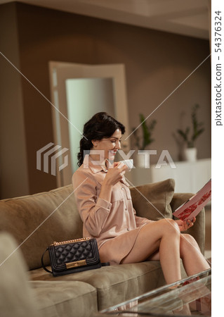 Woman drinking tea and reading magazine waiting for doctor 54376324