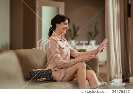 Woman smiling while reading beauty magazine waiting for doctor Woman smiling while reading beauty magazine waiting for doctor 54376337