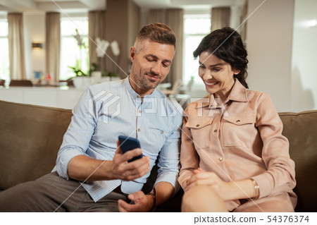 Wife looking at photos of her future nose sitting near husband Wife looking at photos of her future nose sitting near husband 54376374