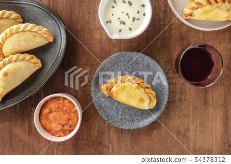 Empanadas with sauces and wine, shot from above on a dark rustic wooden background with a place for 54378312