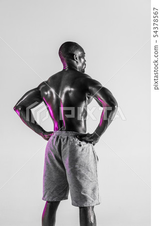 Young african-american bodybuilder training over grey background 54378567