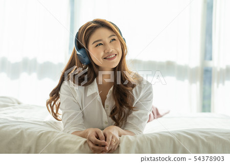 Asian young woman listen music and lying on bed Asian young woman listen music and lying on bed 54378903