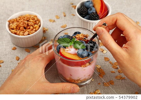 Woman eating muesli granola breakfast with yogurt Woman eating muesli granola breakfast with yogurt 54379902