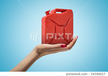 Side closeup of woman's hand facing up and holding red metal jerrican on light blue gradient 54380027