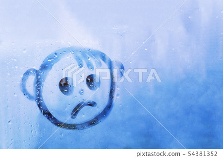 Foggy glass on blue window with drawn sad face concept photo Foggy glass on blue window with drawn sad face concept photo 54381352