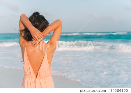 Young beautiful woman on tropical seashore in sunset. Young beautiful woman on tropical seashore in sunset. 54384100