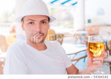 Young man with beer on the beach in outdoors bar Young man with beer on the beach in outdoors bar 54384182