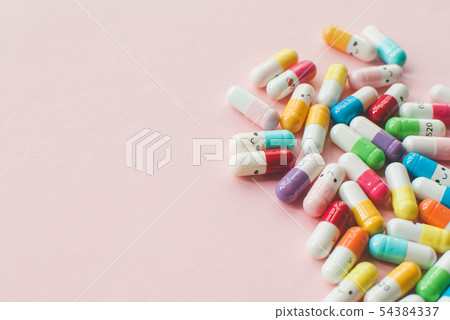 Pile of colored capsule and tablets on a pastel Pile of colored capsule and tablets on a pastel 54384337