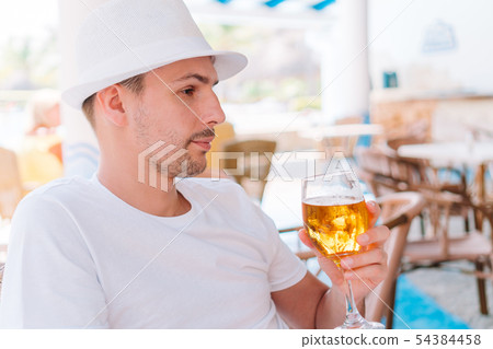 Young man with beer on the beach in outdoors bar 54384458