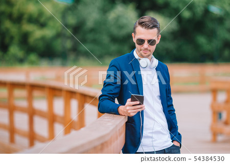 Man is reading text message on mobile phone while walking in the park Man is reading text message on mobile phone while walking in the park 54384530