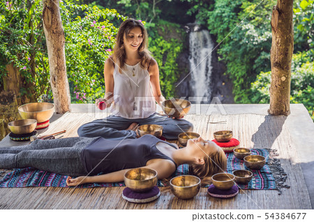 Nepal Buddha copper singing bowl at spa salon. Young beautiful woman doing massage therapy singing 54384677