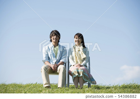 Couple sitting on a chair in the meadow 54386882