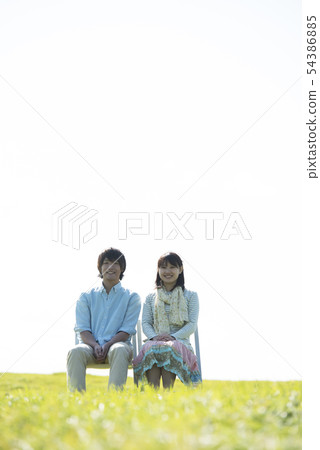 Couple sitting on a chair in the meadow 54386885