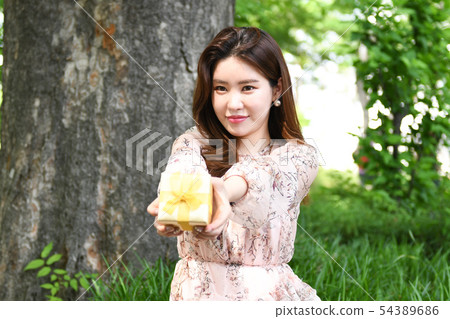 A young woman handing a gift with both hands A young woman handing a gift with both hands 54389686