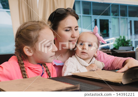 Mom with children in the cafe read the menu Mom with children in the cafe read the menu 54391221