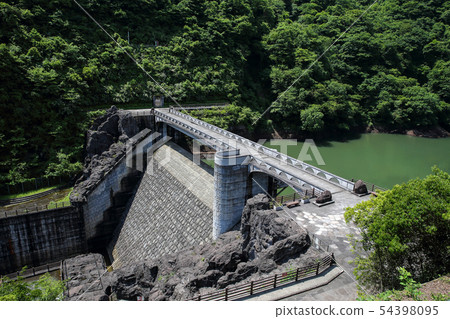 Stone hut dam with green water 54398095