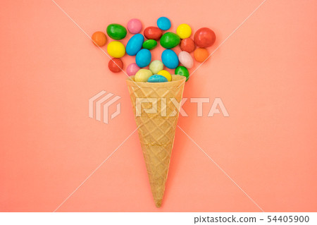 Waffle horn with candy on pink background Waffle horn with candy on pink background 54405900