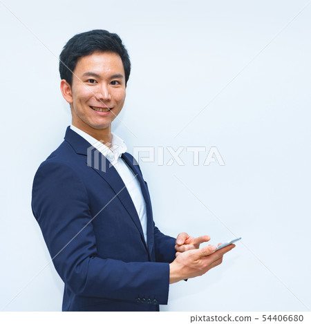 [Business image] A scene where a male office worker is operating a smartphone with cashless payment 54406680