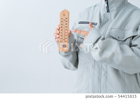 A person in a workwear is pointing at a thermometer A person in a workwear is pointing at a thermometer 54415815