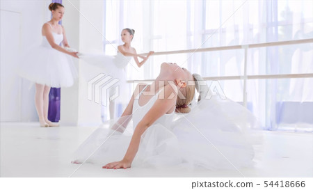 Child girl ballerina in white tutu is doing stretch exercises on ballet lesson. Child girl ballerina in white tutu is doing stretch exercises on ballet lesson. 54418666