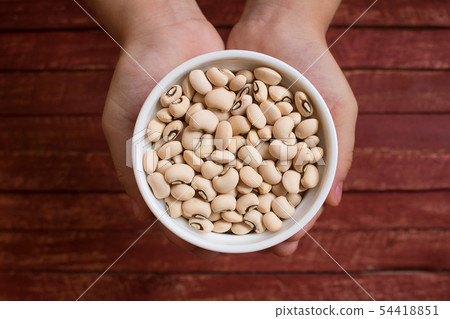 Hands holding black eyed beans in white bowl. Hands holding black eyed beans in white bowl. 54418851