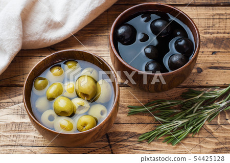 Black and green olives in wooden bowls on wooden Black and green olives in wooden bowls on wooden 54425128