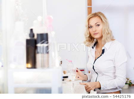 Make up artist doing professional makeup of young woman near the mirror in beauty studio 54425176