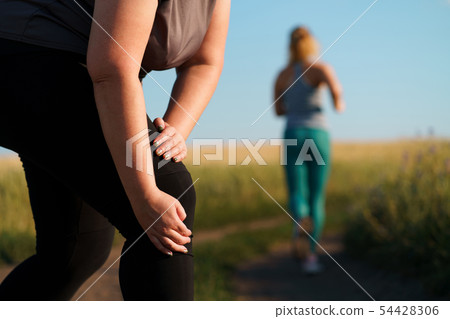 Woman touching her knee, sports injury at jogging 54428306