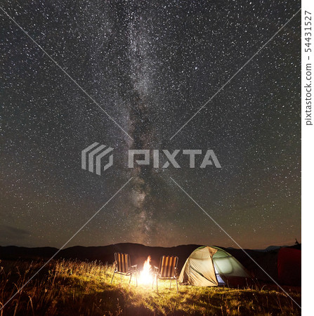 Tourist camping at night in the mountains under starry sky Tourist camping at night in the mountains under starry sky 54431527
