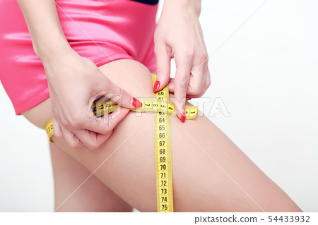 The girl taking measurements of her body, white background. 54433932