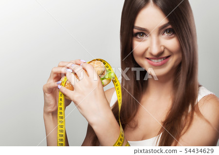 Harmful food. A young girl is struggling with overweight and malicious food. The choice between 54434629