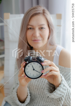 Blonde young woman holding a black clock Blonde young woman holding a black clock 54435758