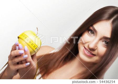Diet. Emaciation. Girl smiles while holding an apple in her arms. Sports and fitness. The concept of Diet. Emaciation. Girl smiles while holding an apple in her arms. Sports and fitness. The concept of 54436254