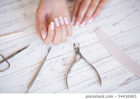 Manicure. Close up female hands situating on desk near nail tools 54436965