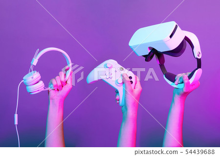 Set of hands with gamepad, virtual reality headset and headphones on violet background. 54439688