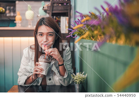 Asian woman drinking coffee in a cafe. 54440950