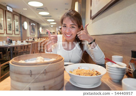 Asian woman show thumbs up sign and eating soup 54440957