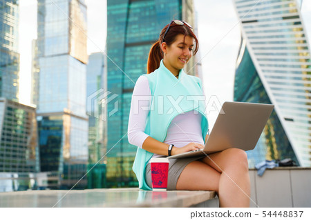 Portrait of business woman sitting with laptop and cup of coffee Portrait of business woman sitting with laptop and cup of coffee 54448837