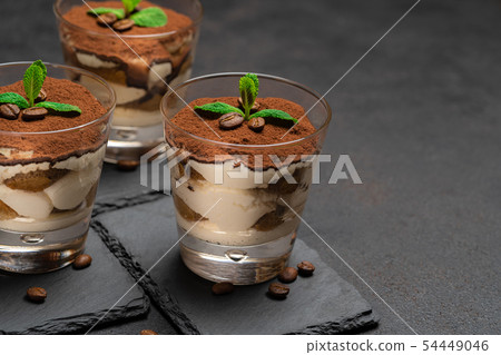 Classic tiramisu dessert in a glass on stone serving board on dark concrete background 54449046