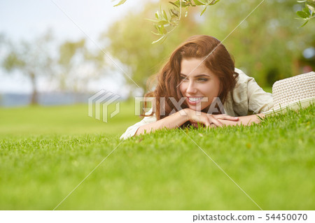 Beautiful smiling woman lying on a grass outdoor. Beautiful smiling woman lying on a grass outdoor. 54450070
